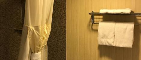 A bathroom with a shower curtain, a towel rack with two towels, and a wooden wall.