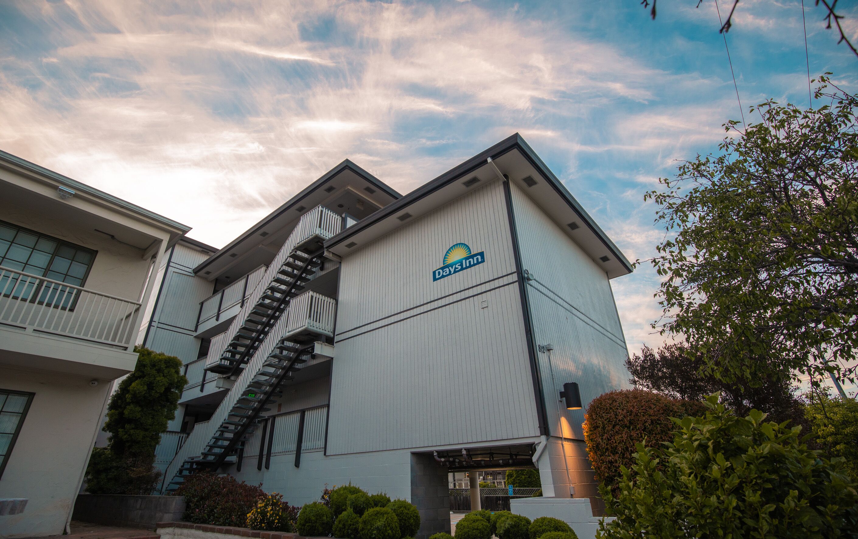 A Days Inn building with a prominent staircase leading to the entrance, surrounded by greenery.