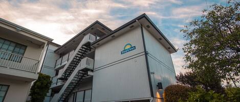 A Days Inn building with a prominent staircase leading to the entrance, surrounded by greenery.