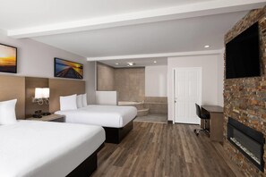 A hotel room with two beds, a desk, a TV, a fireplace, and a bathroom with a shower and sink. - Days Inn by Wyndham Monterey Downtown (Monterey)