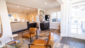 A modern hotel lobby with a reception desk, seating area, and a coffee machine. - Days Inn by Wyndham Monterey Downtown (Monterey)