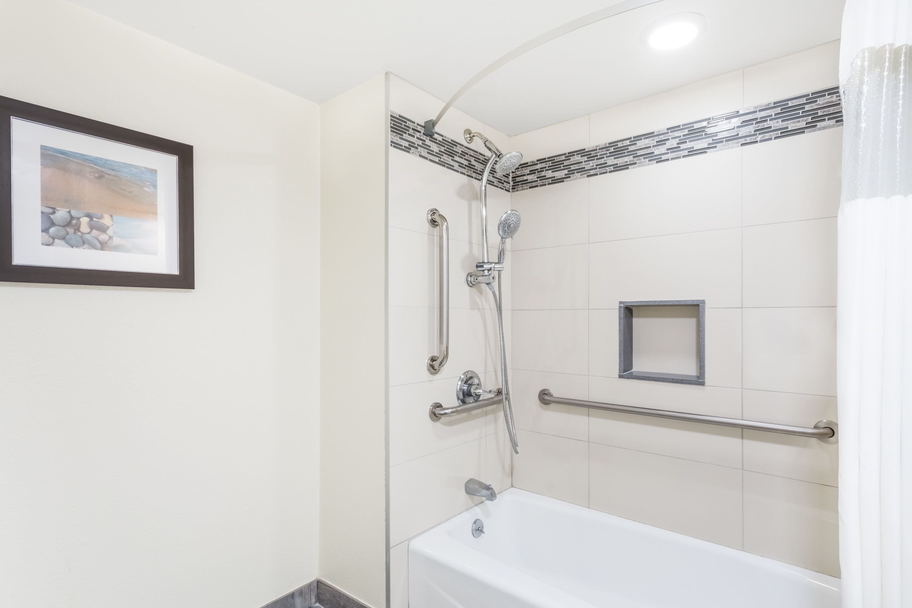 Un baño moderno con ducha, bañera y barra de apoyo.