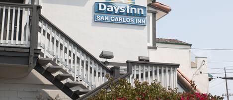 A Days Inn with a staircase leading to the entrance, surrounded by well-maintained hedges and flowering plants.