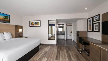 A hotel room with a bed, desk, and kitchenette.