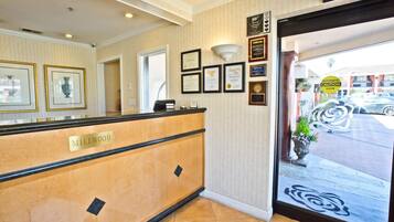 A reception area with a marble counter labeled "Millwood," framed certificates on the wall, and a "CAUTION DOOR" sign.