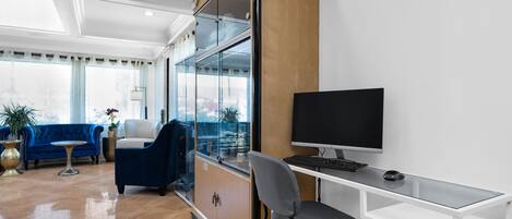 A modern room with a glass desk, a computer, a blue sofa, and a large cabinet.