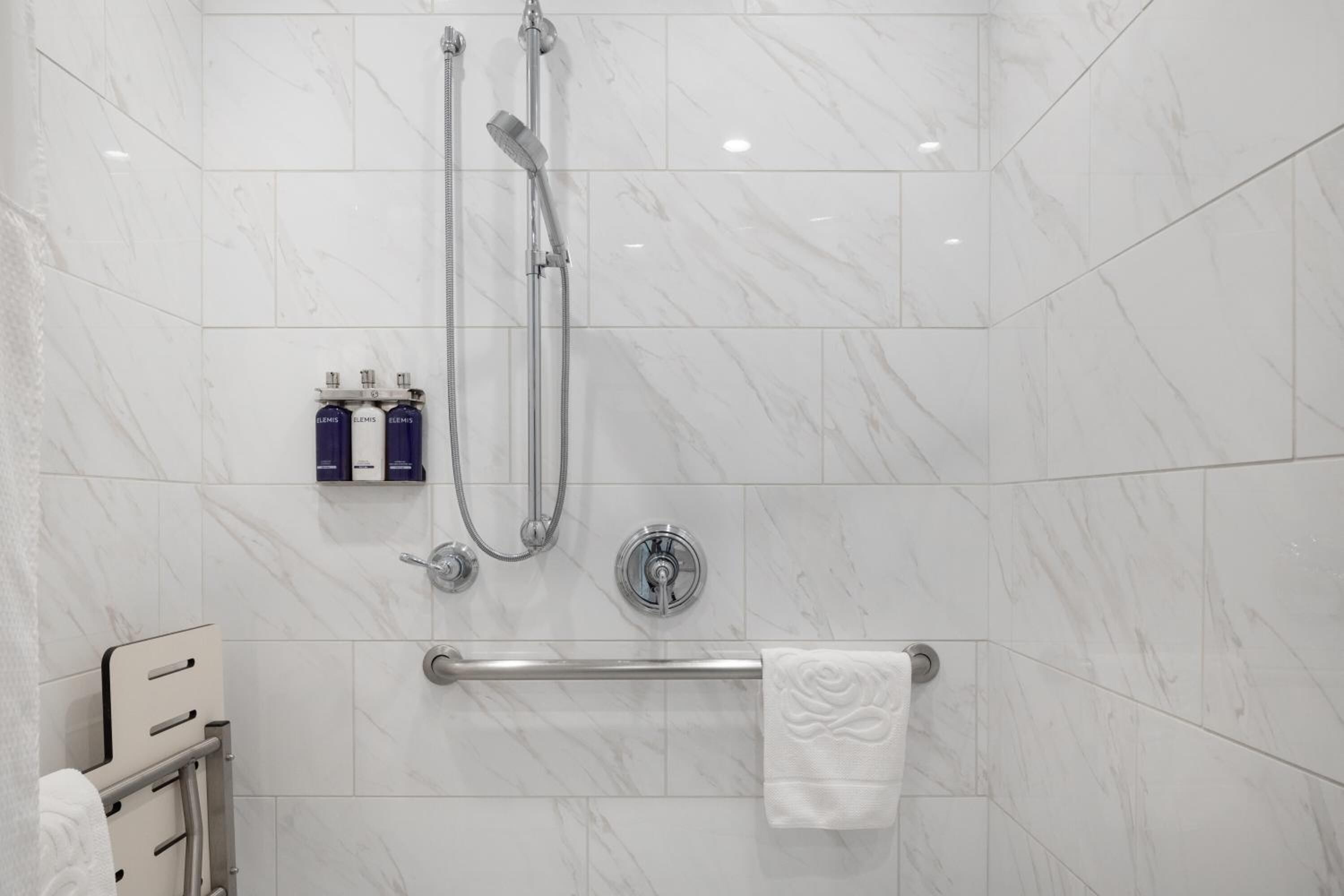 A modern bathroom with a shower, a hand dryer, and a towel rack.