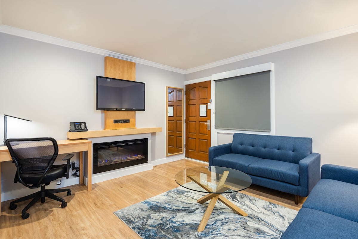 Una sala de estar moderna con chimenea, televisor, sofá y escritorio con computadora.