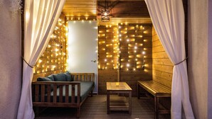 Una habitación acogedora con paredes de madera, un banco, una mesa y luces colgantes.