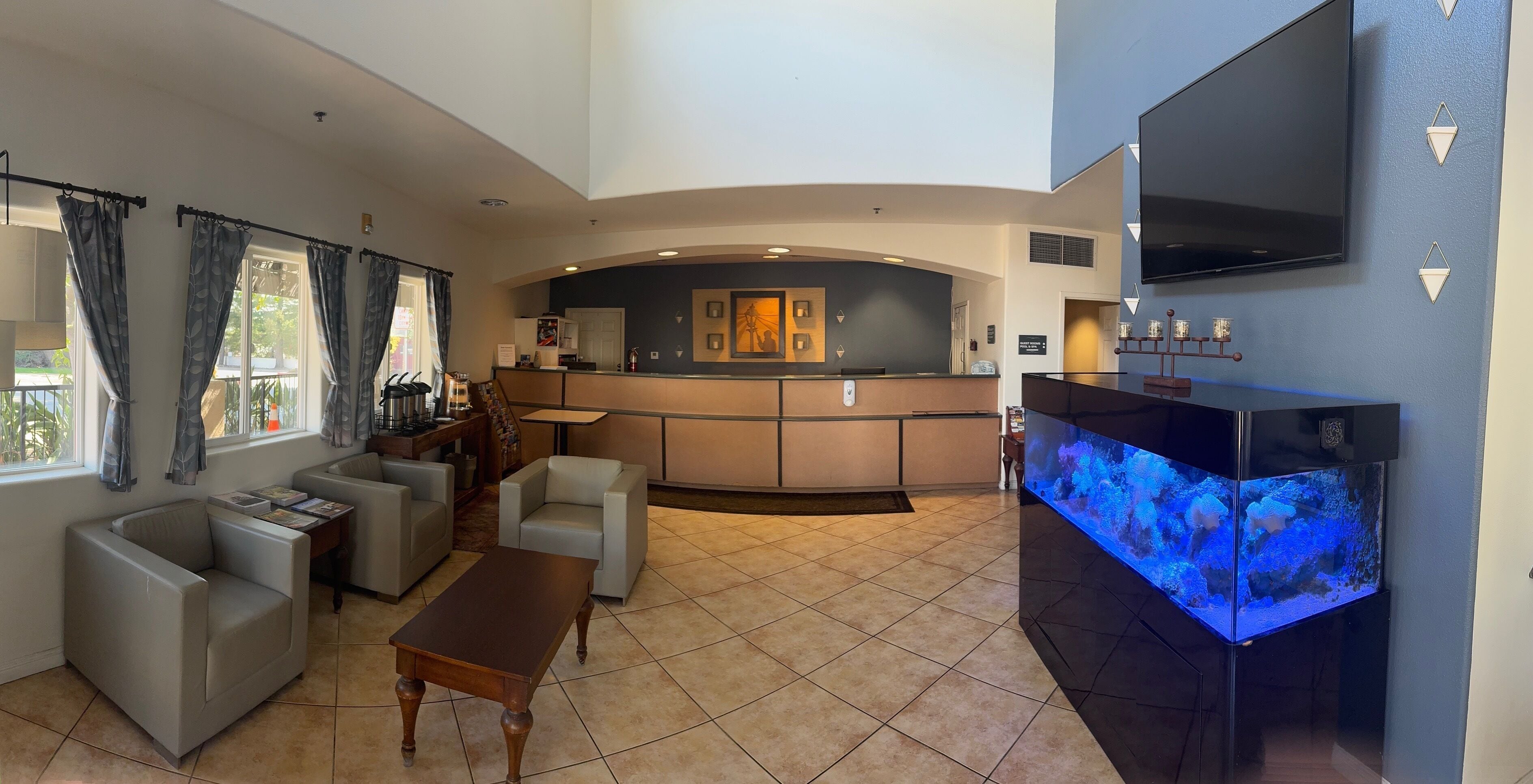 A hotel lobby with a reception desk, seating area, and a large aquarium.