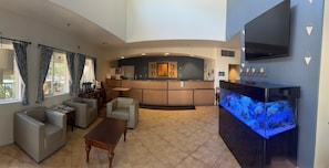 A hotel lobby with a reception desk, seating area, and a large aquarium. - Lamplighter Inn & Suites (San Luis Obispo)