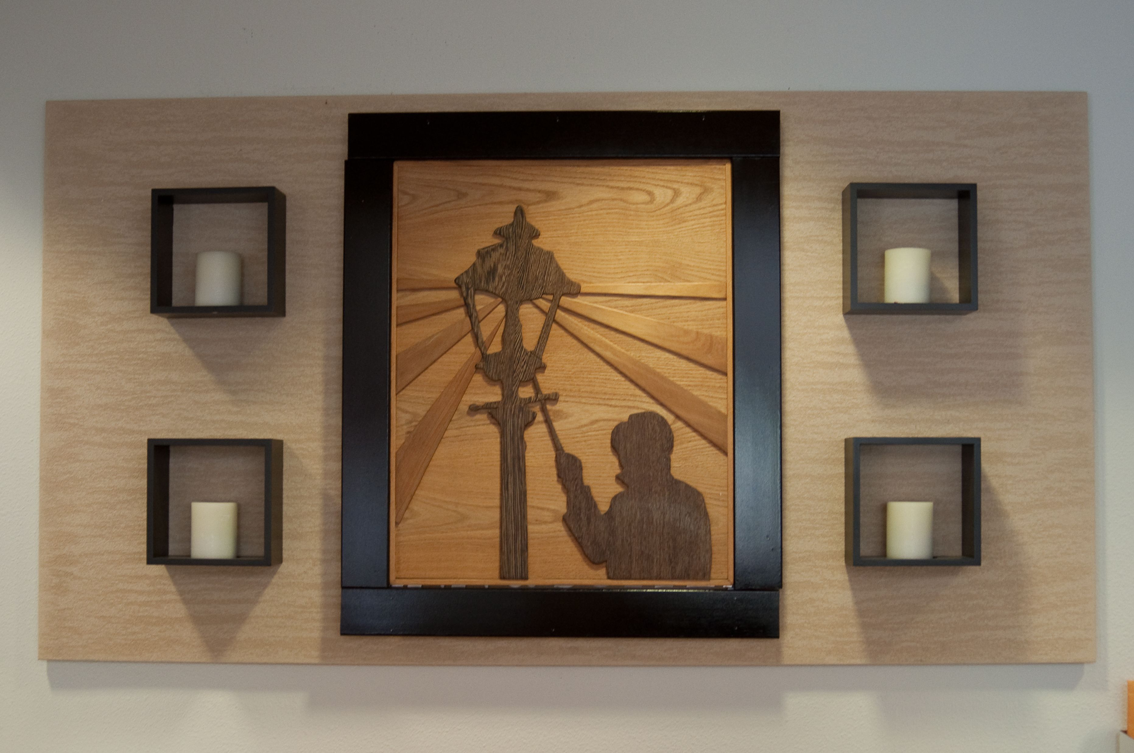 A wall-mounted wooden panel with a central relief sculpture of a figure holding a staff.