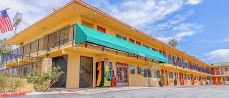 Un motel con fachada amarilla, toldo verde y puerta roja.