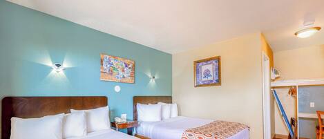 Habitación de hotel con dos camas, cabecera de madera, mesita de noche, lámpara de pared e imagen enmarcada.