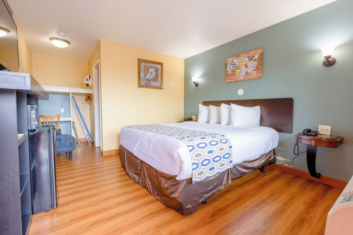 Ein Schlafzimmer mit Bett, Schreibtisch, Stuhl und Kühlschrank.