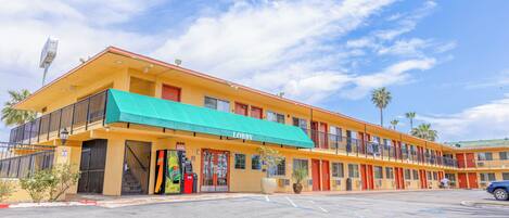 A motel with a green awning, multiple balconies, and a parking lot.