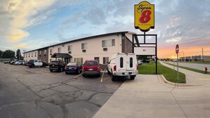 A Super 8 motel with a parking lot, a white truck, and a sunset in the background. - Super 8 by Wyndham West Fargo Main Ave ND (West Fargo)
