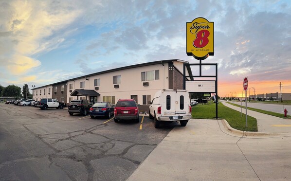 Et Super 8 motel med parkeringsplads, en hvid varevogn og en solnedgang i baggrunden.