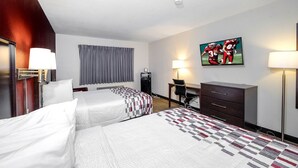 Een hotelkamer met twee bedden, een bureau, een stoel, een dressoir en een televisie aan de muur.