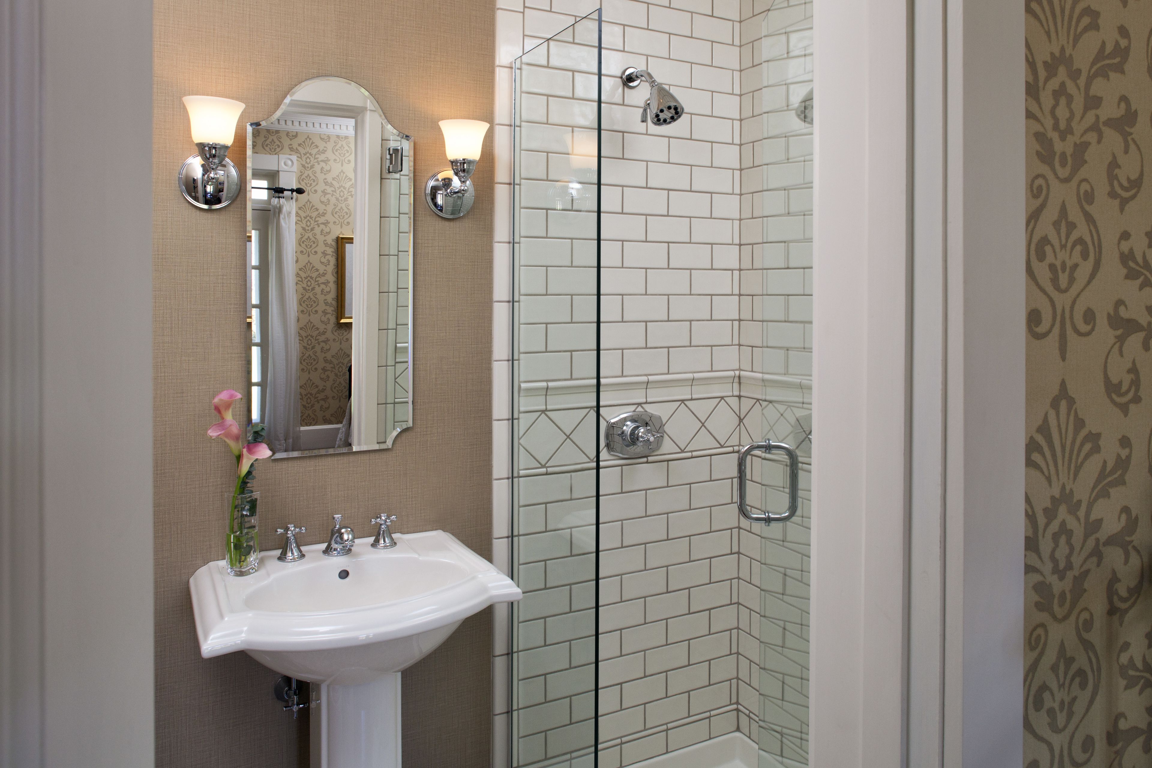 Un baño con lavamanos blanco, espejo y cabina de ducha de vidrio.