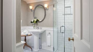 A bathroom with a white sink, mirror, and glass shower enclosure.