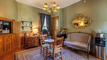 Una habitación con una mesa de comedor, sillas, un sofá, una araña, un espejo y un minibar.