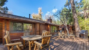 Une cabane en bois dotée d’une terrasse, d’un espace salon extérieur et d’un barbecue.