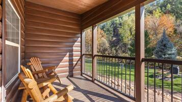 Une terrasse en bois, avec des chaises, donnant sur une zone boisée.