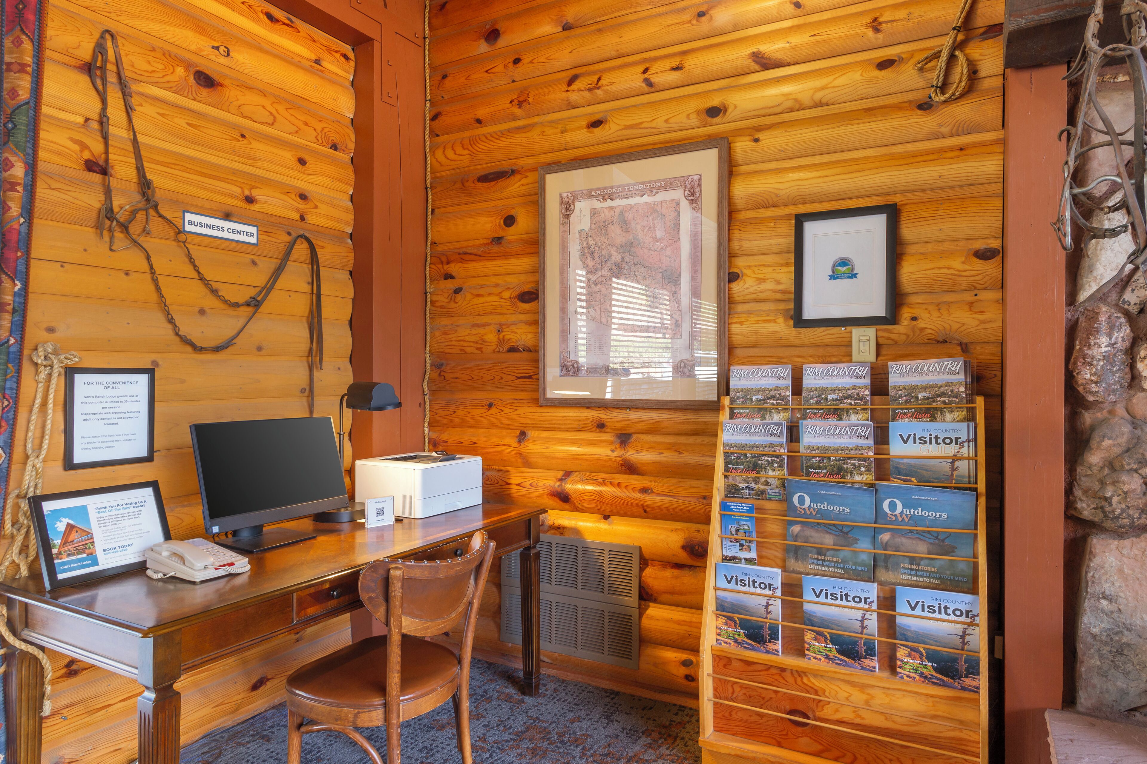A wooden interior with a desk, computer, and framed pictures on the wall.