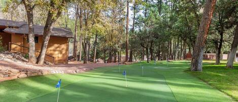 A golf course with a clubhouse, surrounded by trees.