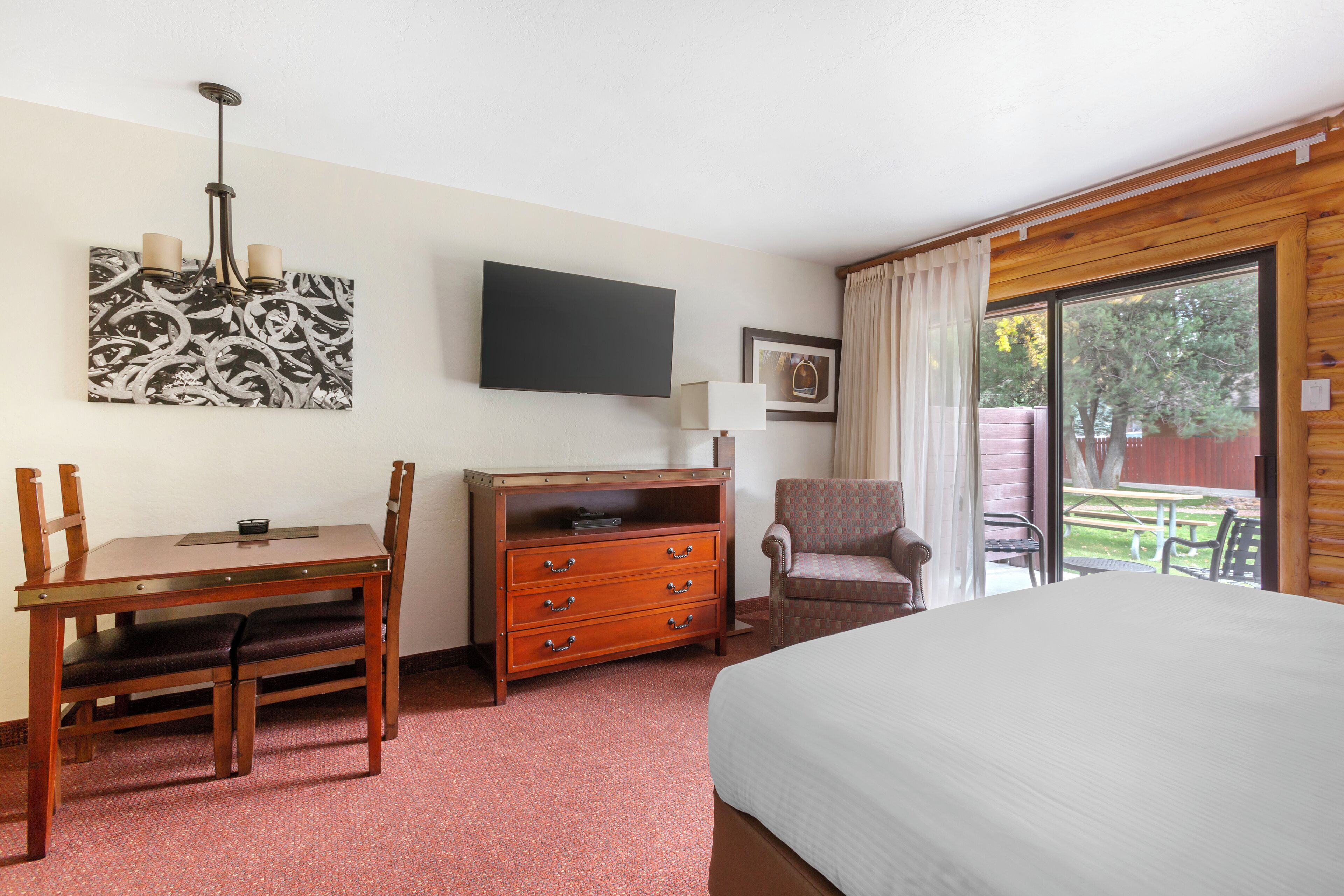 Une chambre d’hôtel comprenant un lit, un bureau avec une chaise, une commode, un téléviseur et une vue sur l’extérieur.