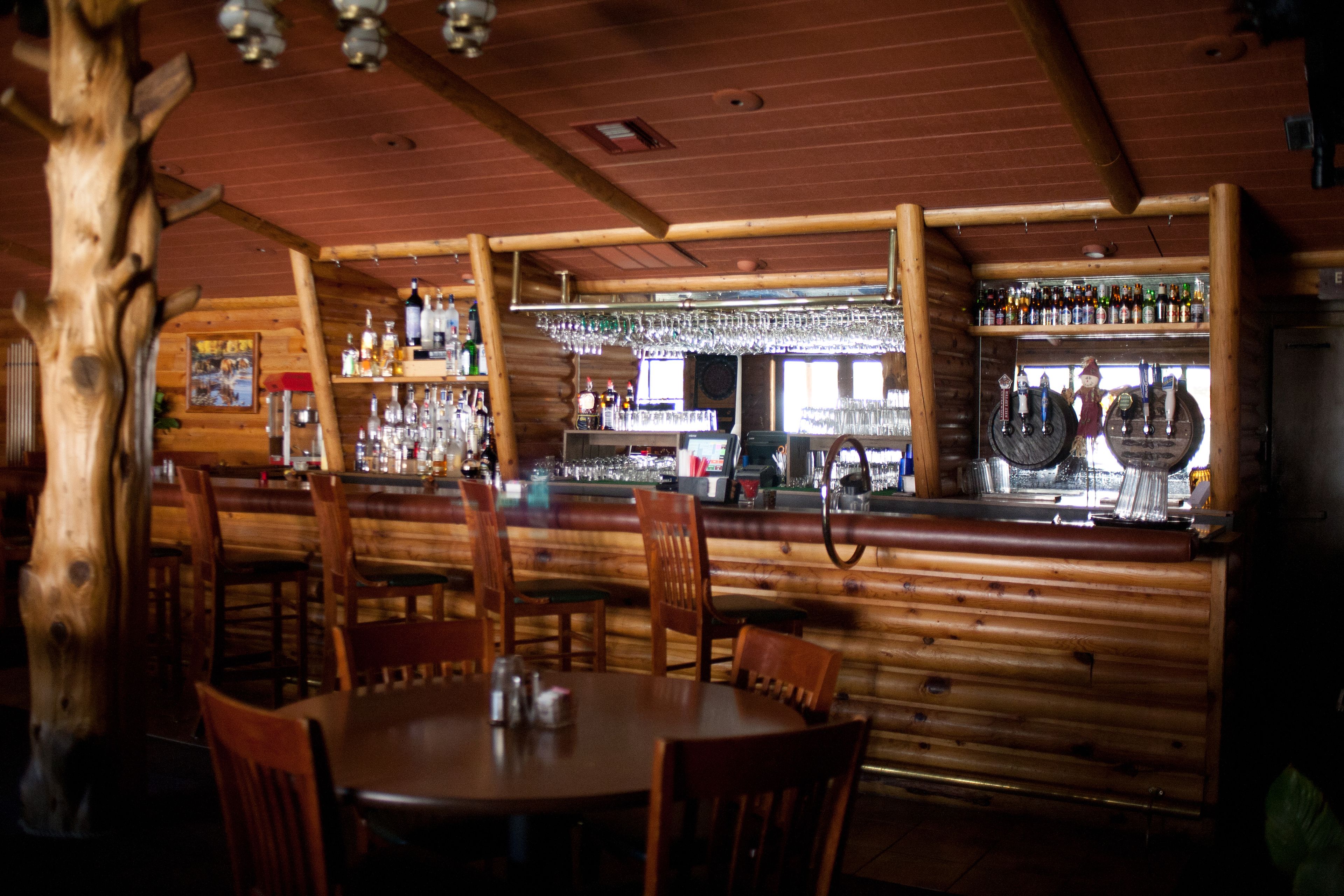 A rustic bar area with wooden walls, a bar counter, and seating.