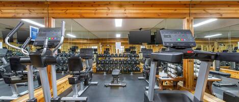 A gym with treadmills, elliptical machines, and a wall of dumbbells.