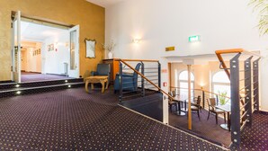 Un hall de hotel con una escalera, una recepción y una zona de estar.