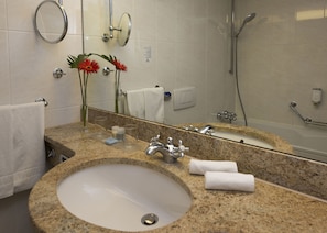 Enjoy a refreshing shower in the spacious bathroom with a large sink, glass shower enclosure, and ample mirror space.