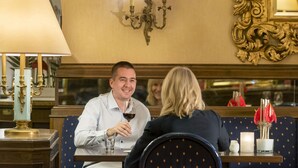 Un coin repas comprenant une table, des chaises, un chandelier et un miroir au mur.