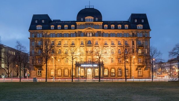 Un bâtiment historique doté d’un dôme imposant et de plusieurs étages, portant l’inscription « Parkhotel 1901 ».