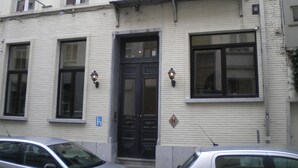 Un edificio con fachada blanca, puerta negra y dos ventanas con marcos negros.