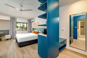 Una habitación de hotel moderna con una cama, un escritorio, un ventilador de techo y un ventanal grande.
