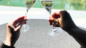 Two hands holding wine glasses with a pool and palm trees in the background. - Mercure Cairns (Cairns)