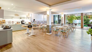 A spacious dining area with wooden flooring, white walls, and a central island with kitchen equipment. - Mercure Cairns (Cairns)