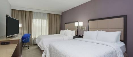 A hotel room with two beds, a desk, a TV, and a chair.