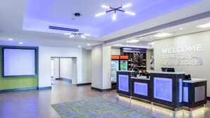 A reception area with a modern design, featuring a reception desk, a welcome sign, and a vending machine. - Hampton Inn & Suites Jacksonville / Orange Park (Orange Park)
