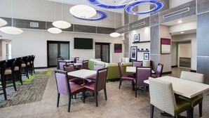 A modern hotel lobby with multiple seating areas, including tables and chairs, and a reception desk. - Hampton Inn & Suites Jacksonville / Orange Park (Orange Park)
