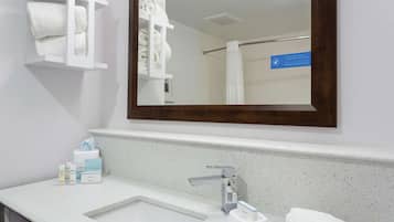Une salle de bain avec un lavabo blanc, un miroir et un porte-serviettes.