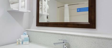 Un bagno con un lavandino bianco, uno specchio e un portasciugamani.