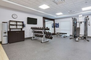 A gym with a weight rack, dumbbells, a bench, and a mirror. - Hampton Inn & Suites Jacksonville / Orange Park (Orange Park)