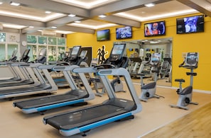 Un gimnasio con cintas de correr, bicicletas estáticas y equipamiento de ejercicio.