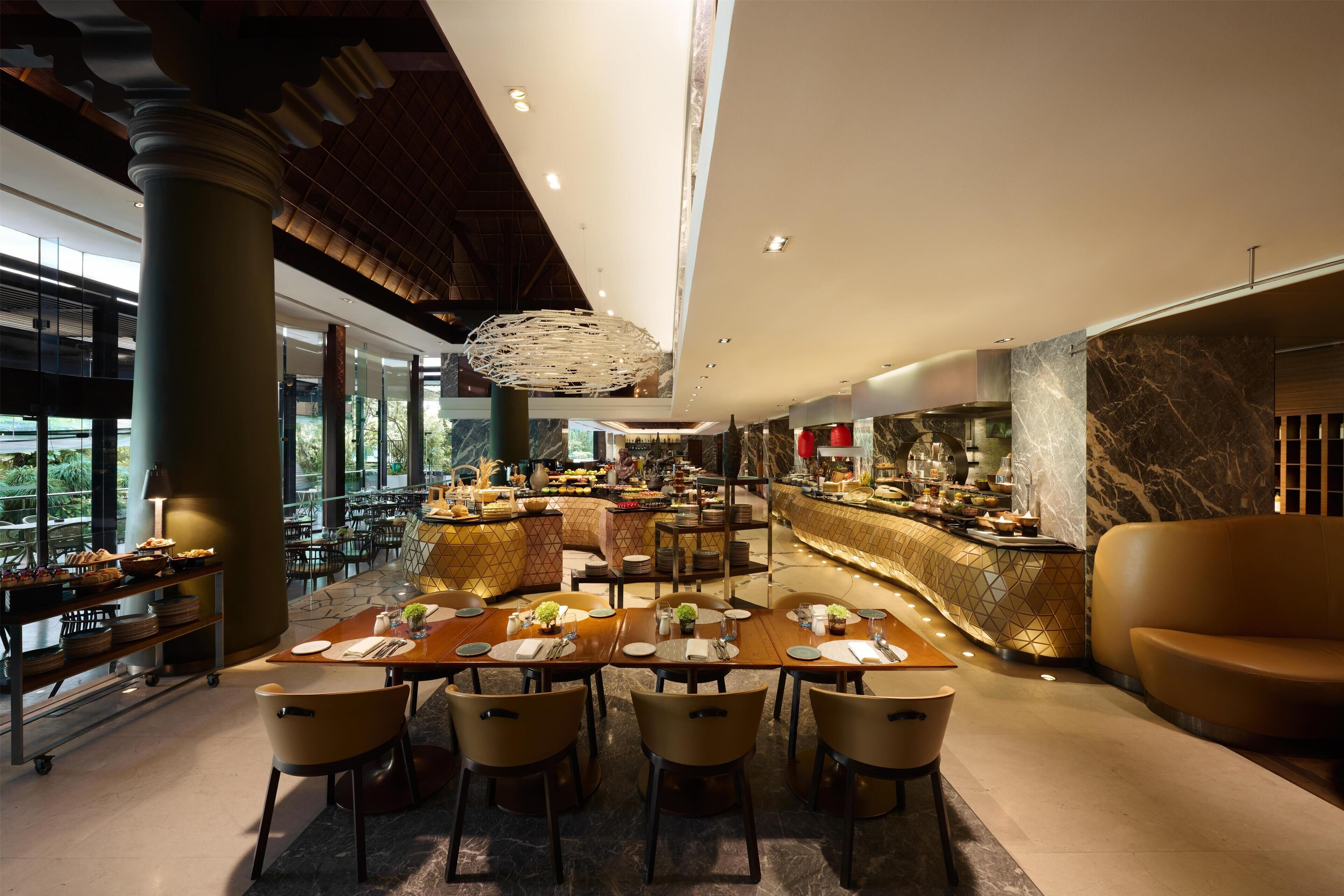 Un restaurante moderno con una barra central, varias mesas para comer y vistas al exterior.