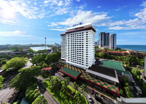 A Hilton hotel with a modern design, surrounded by lush greenery and a view of the ocean.